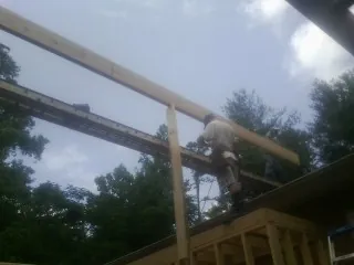 Carpenter setting a ridge beam over a new addition frame — Ice Dam Removal by Roofing Brothers in Marshalltown