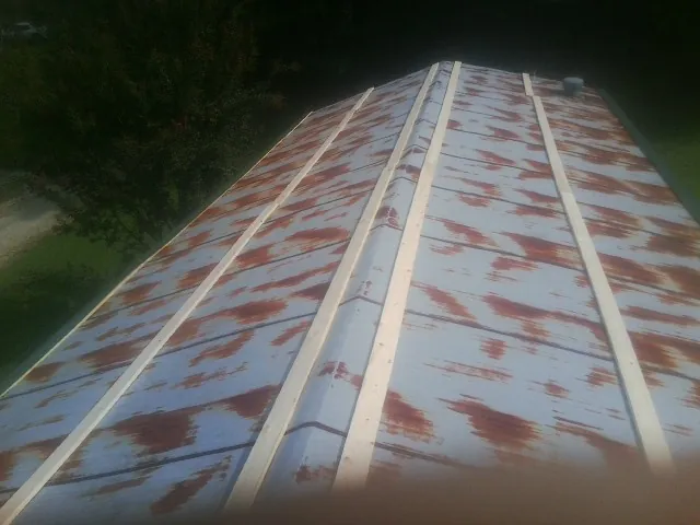 Rusted metal roof panels with new wood purlins before replacement — Storm Damage Roof Repair in Marshalltown by Roofing Brothers