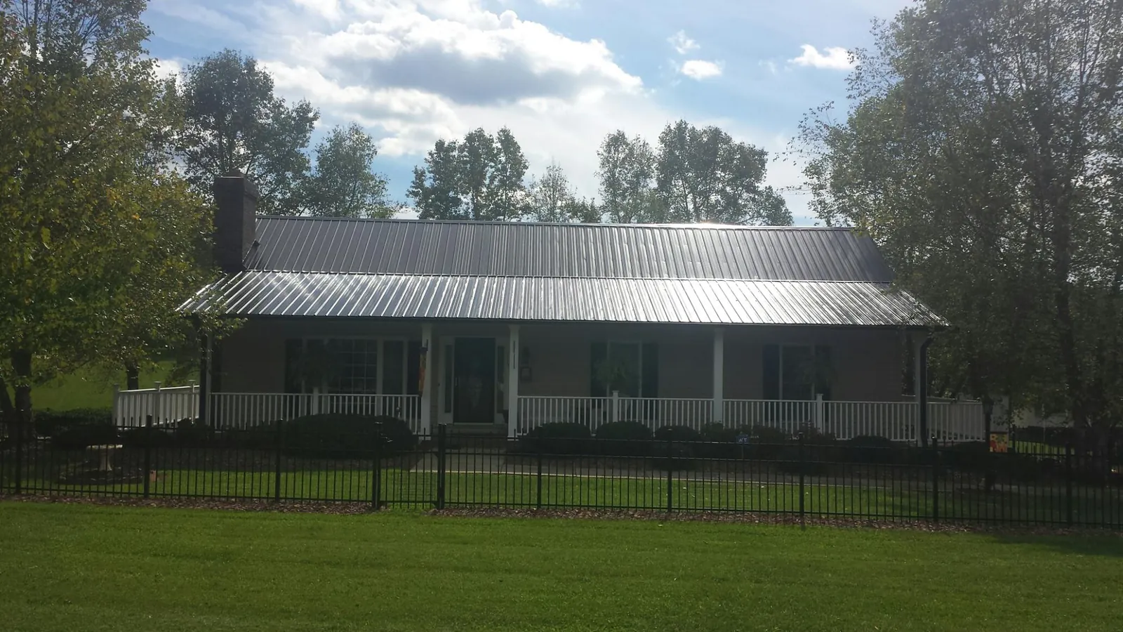 Gray metal roof on a brick ranch with a full width front porch — Gutter Guard Installation work by our crew in Marshalltown