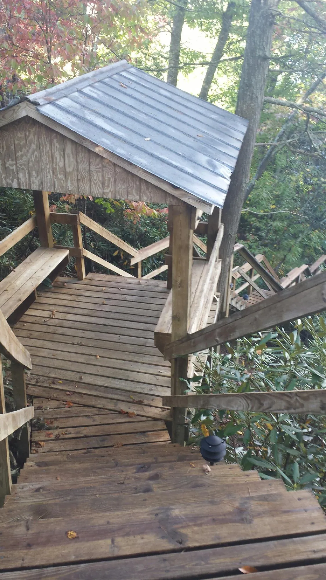 Metal roofed shelter over wooden steps on a wooded walkway — Skylight Repair & Installation work by our crew in Marshalltown
